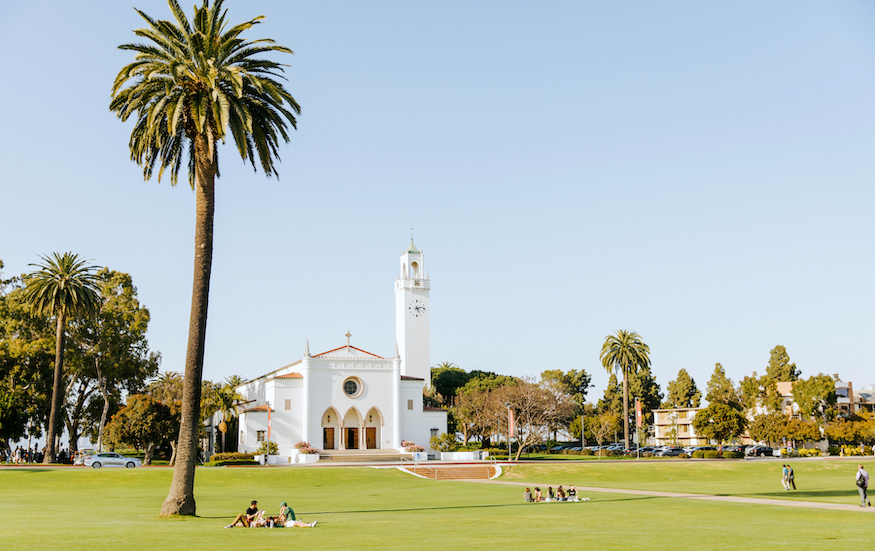 Image of Sacred Heart Chapel with students lounging on Sunken Garden